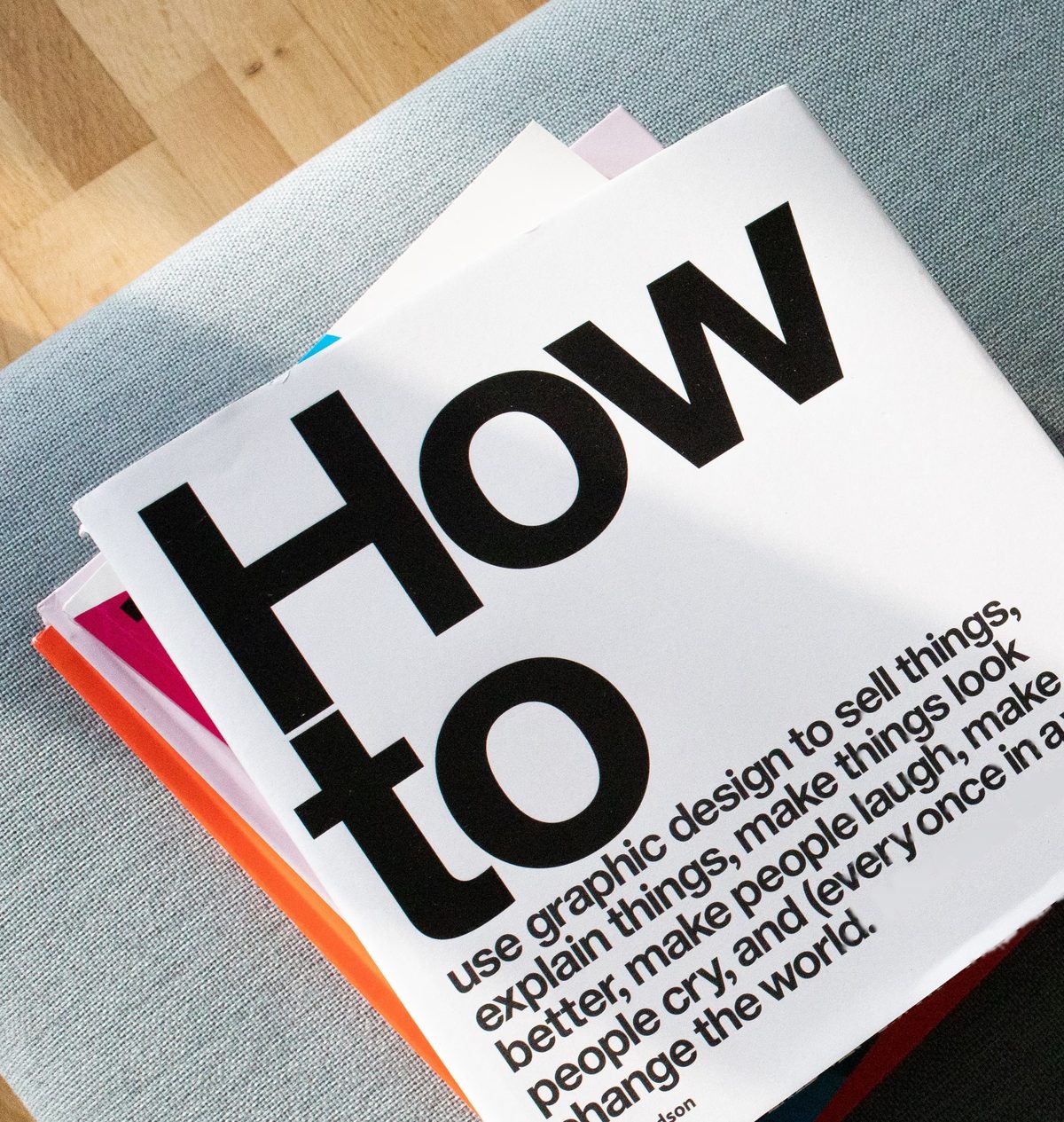 Livre de design graphique « How to » posé sur un canapé